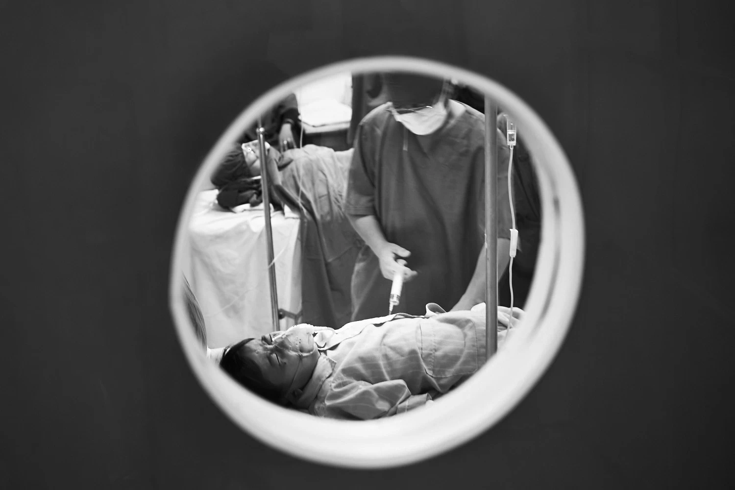 View through a small door window on boy getting an injection just before surgery