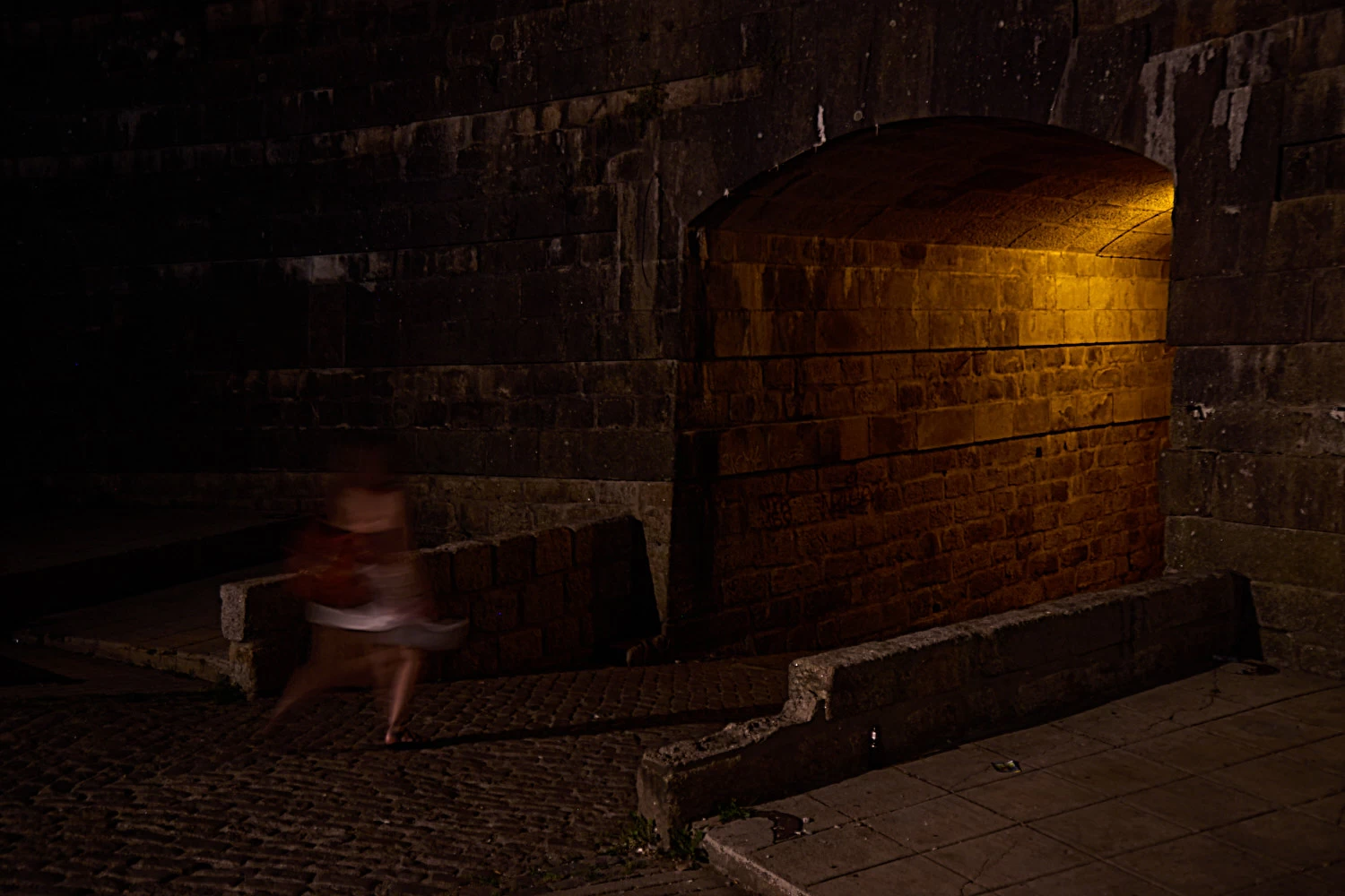 Blurry woman walking towards tunnel with light in Porto