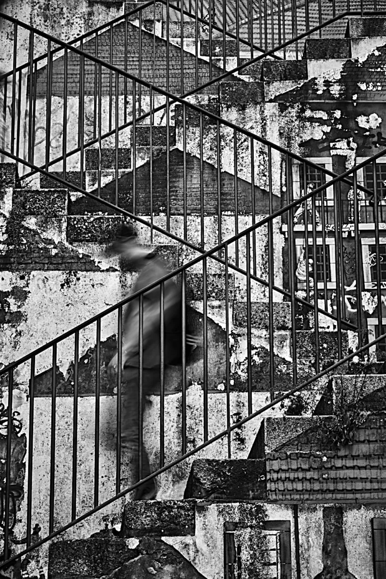 Blurry man walking down stairs, surrounded by symmetry, in Porto