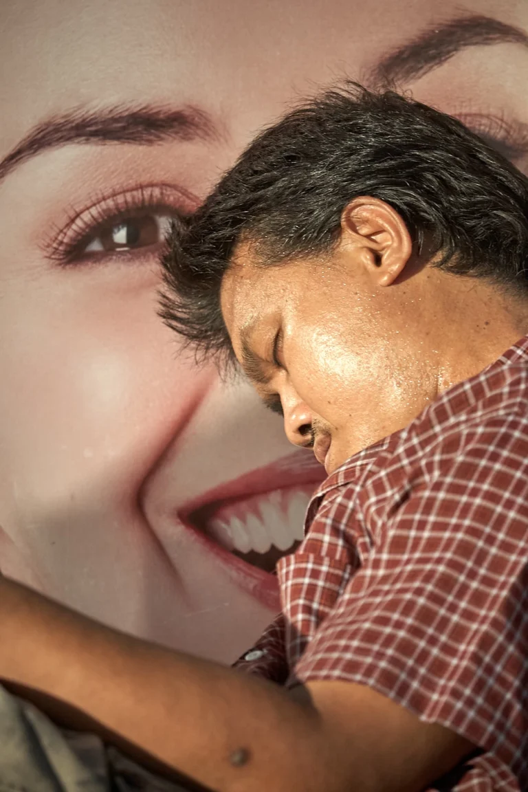 Man sleeping/dreaming with huge billbord with woman behind him, in Bangkok