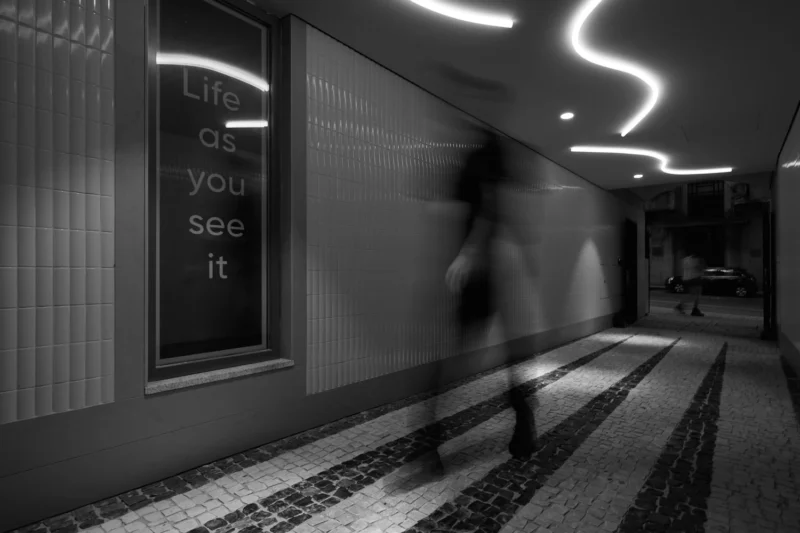 Blurry man in atmospheric corridor in Porto, with a phrase on the wall that relates.