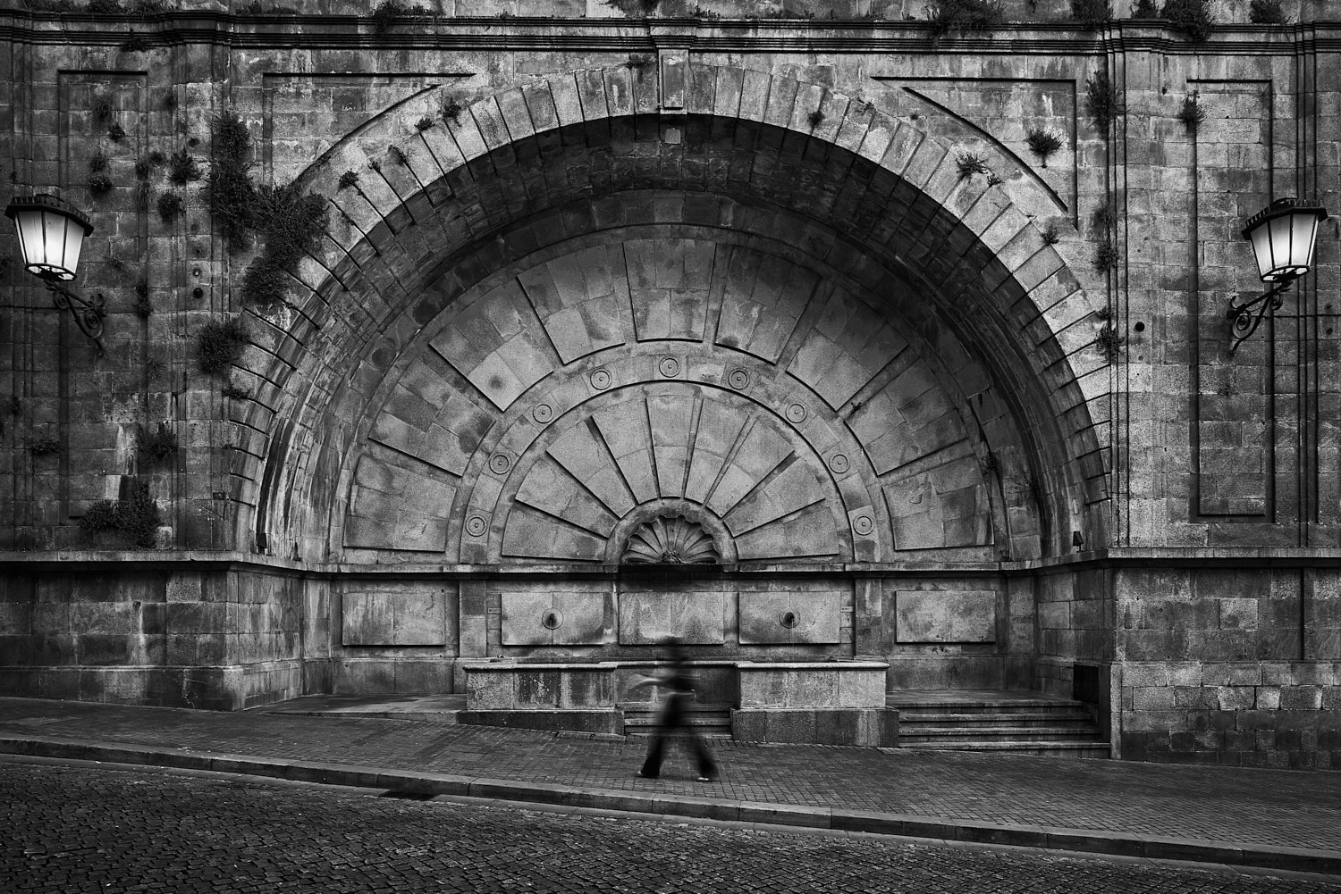 Blurred man walking in front of Fonte Monumental de Mouzinho da Silveira, Porto